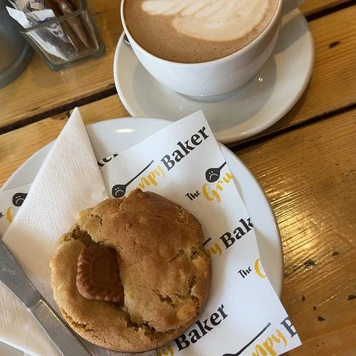 Cookie and coffee on Bath Grumpy Baker-branded paper in a September 2026 visitor photo